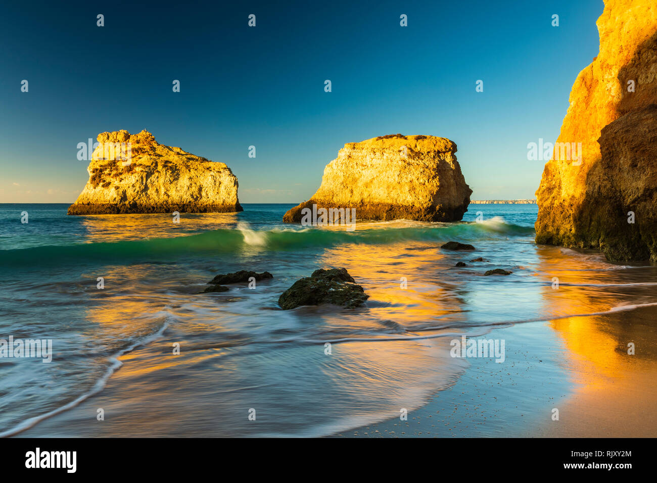 La luce del sole illuminando le formazioni rocciose in mare, Alvor, Algarve, Portogallo, Europa Foto Stock