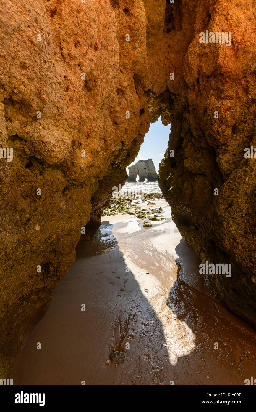 Guardando attraverso la stretta apertura nella caverna di paesaggi costieri, Alvor, Algarve, Portogallo, Europa Foto Stock