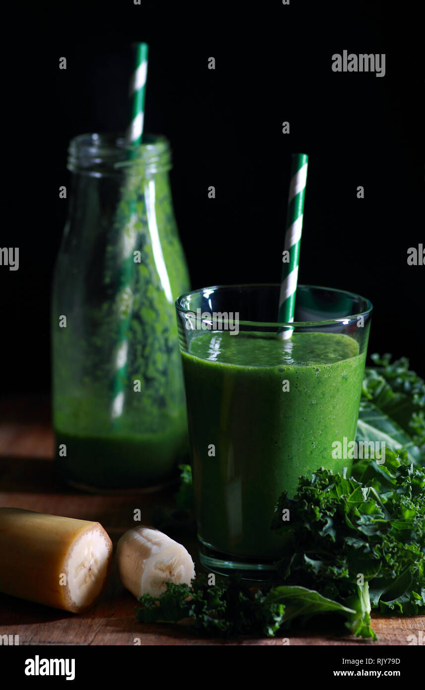 Green sano frullato di cavolo riccio in vetro su sfondo scuro Foto Stock