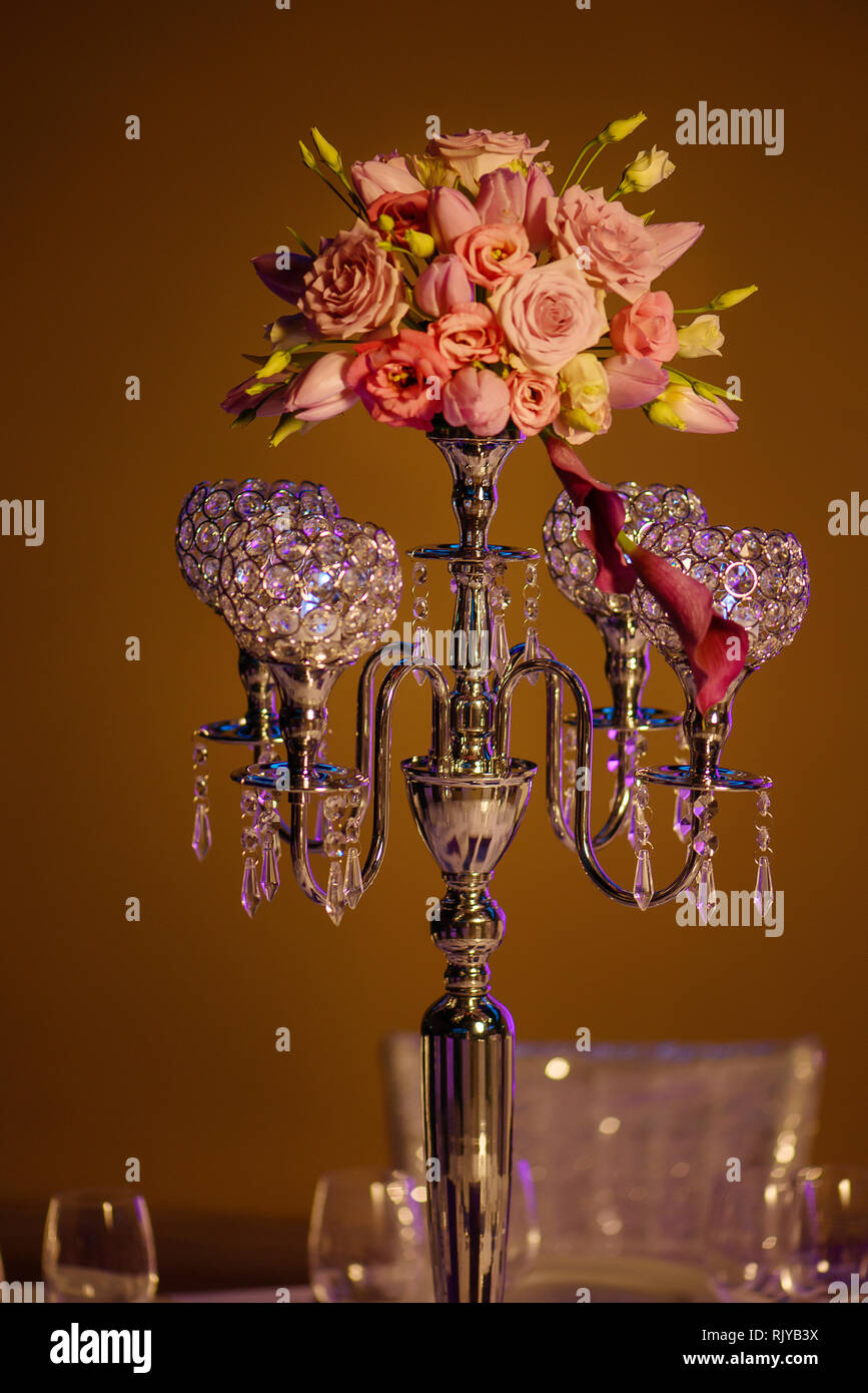 Tabella centrotavola, una bella candelabri di cristallo style portacandele con quattro cave scavate progettato ciotole per candelieri con un bouquet di fiori sulla parte superiore Foto Stock