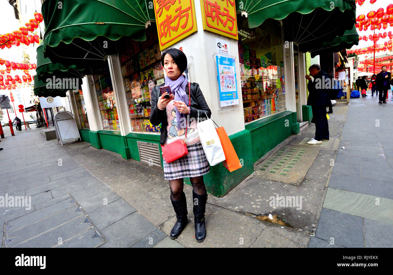 Londra, Inghilterra, Regno Unito. Gerrard Street, Chinatown. Donna che utilizza il suo telefono cellulare Foto Stock