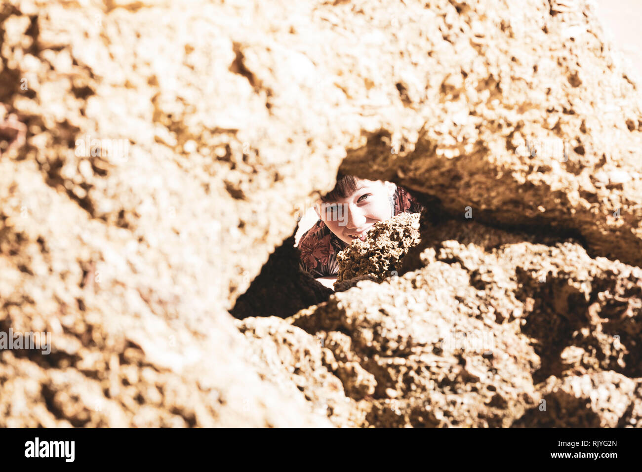 Ritratto di ragazzo del peering attraverso l'apertura di formazione di roccia, Alvor, Algarve, Portogallo, Europa Foto Stock