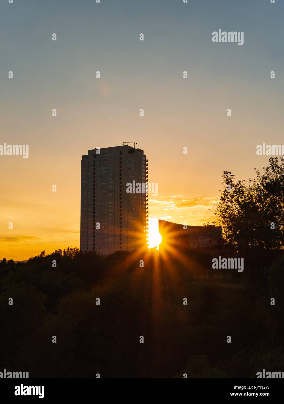Set di sole tra la torre e moderno edificio, Puebla Messico Foto Stock