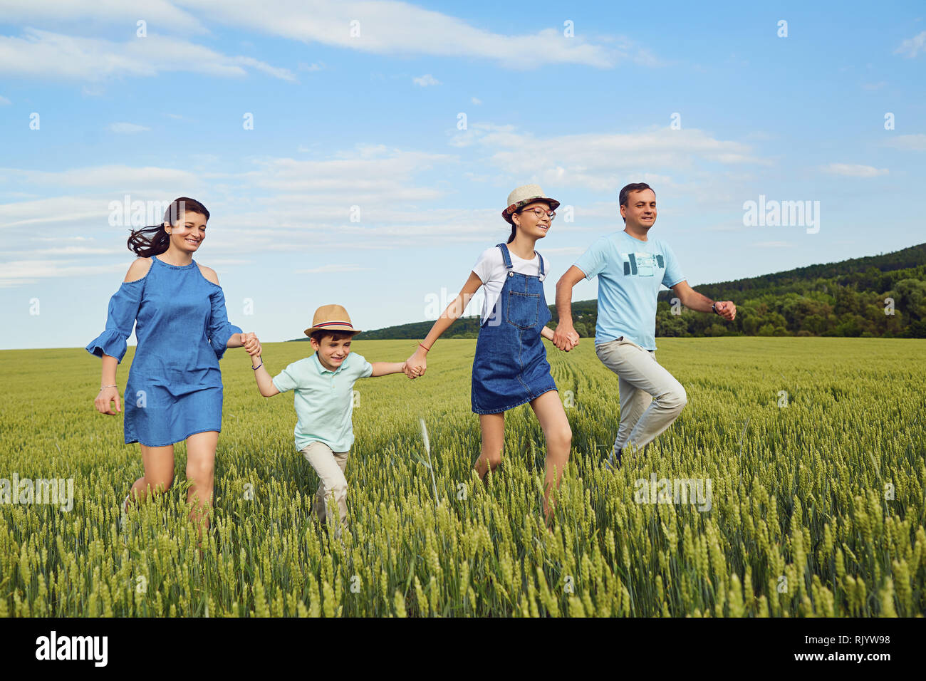 La famiglia felice sorridente in esecuzione sul campo nella natura Foto Stock