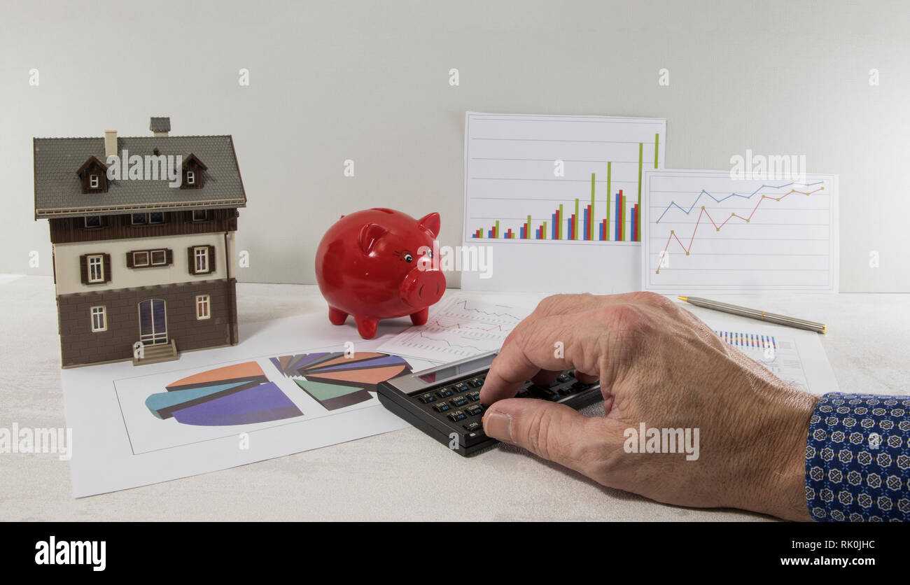 Le mani di un uomo spingendo la calcolatrice, come un business e gli investimenti finanziari con un modello di una casa o di pianificazione della costruzione di una casa Foto Stock