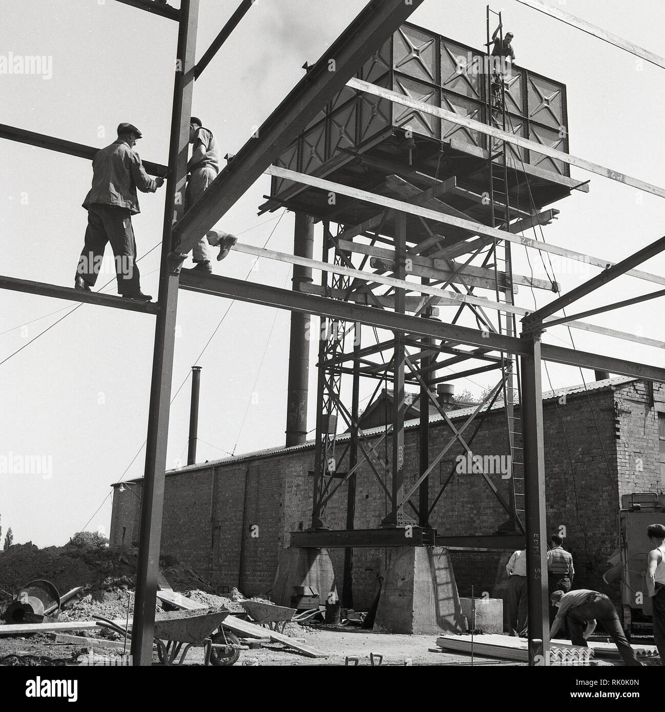 Degli anni Cinquanta, storico, uomini al lavoro su di un edificio o di un sito di costruzione di una nuova fabbrica...non è un elmetto in vista! Foto Stock