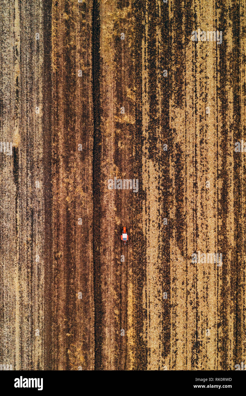 Vista aerea del trattore agricolo campo di aratura in autunno freddo pomeriggio da fuco pov Foto Stock