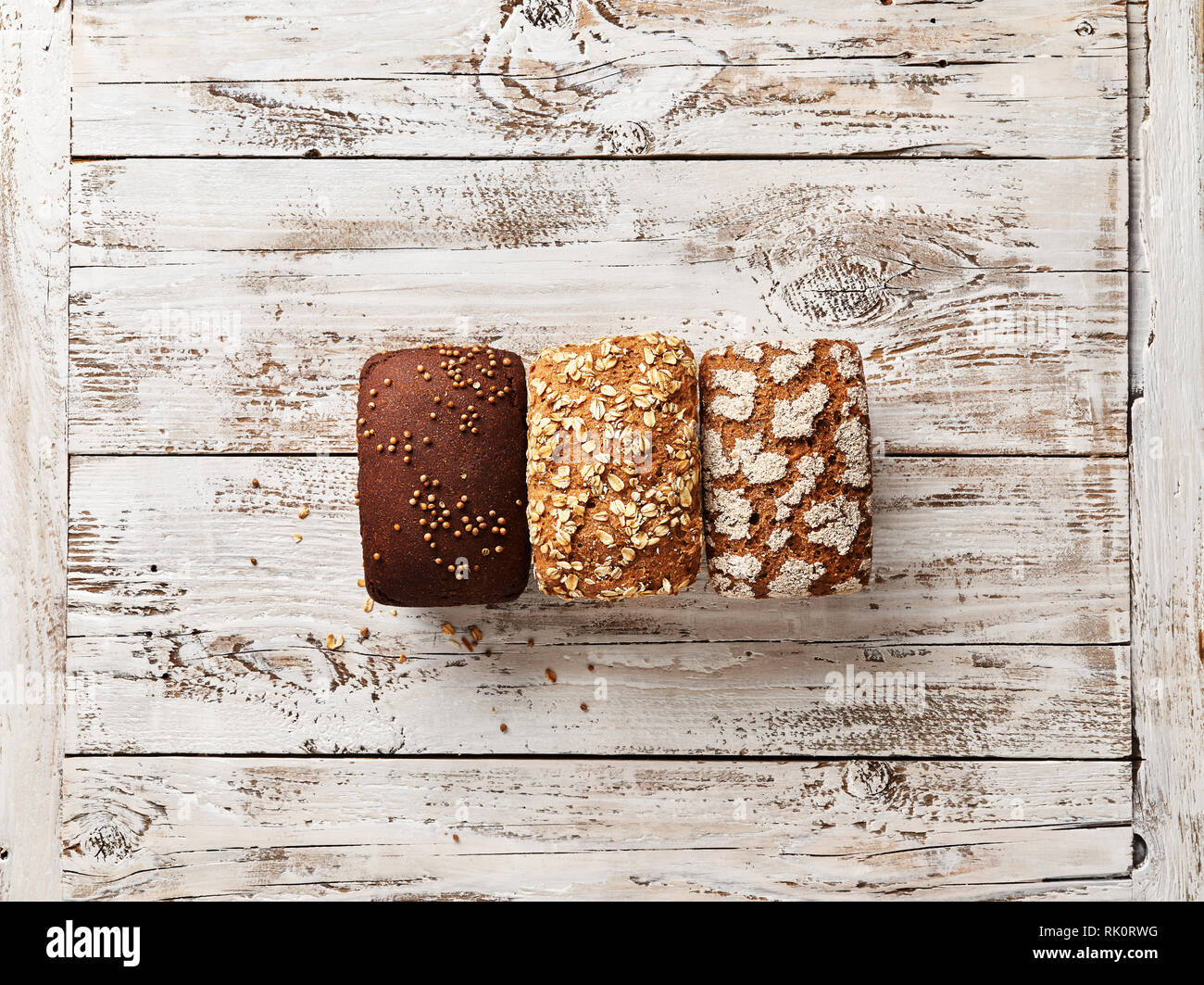 Tre pagnotte di pane bianco su sfondo di legno. Concetto di panetteria con spazio vuoto per il design. Senza glutine pane di segale con crusca e coriandolo Foto Stock