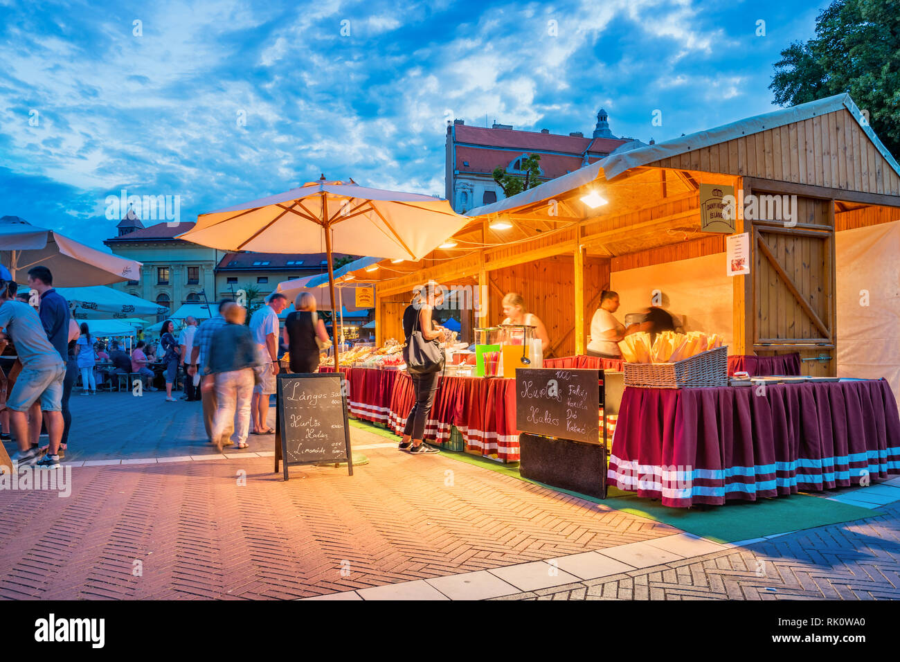 Lo stand di mercato durante un festival nel centro cittadino di Szeged Ungheria vendere langos e kurtoskalacs al crepuscolo. Foto Stock