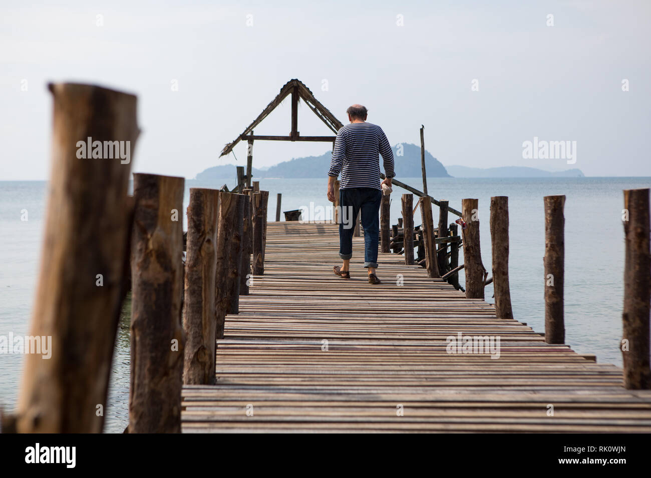 Il vecchio uomo cammina sul molo in riva al mare Foto Stock