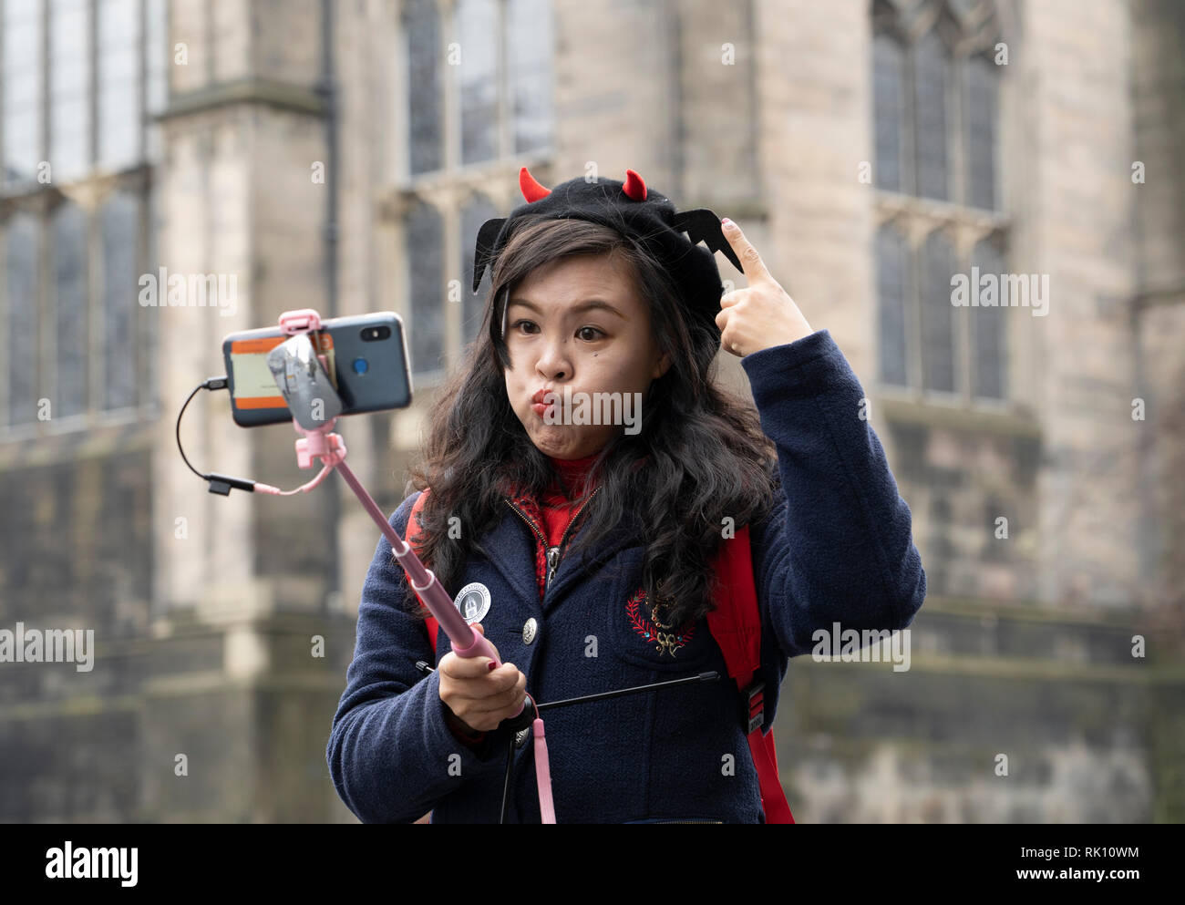 Edinburgh, Regno Unito. 8 Feb 2019. Giovani cinesi turista femminile rendendo divertente faccia tenendo selfie foto nel centro storico di Edimburgo, Scozia, Regno Unito Foto Stock
