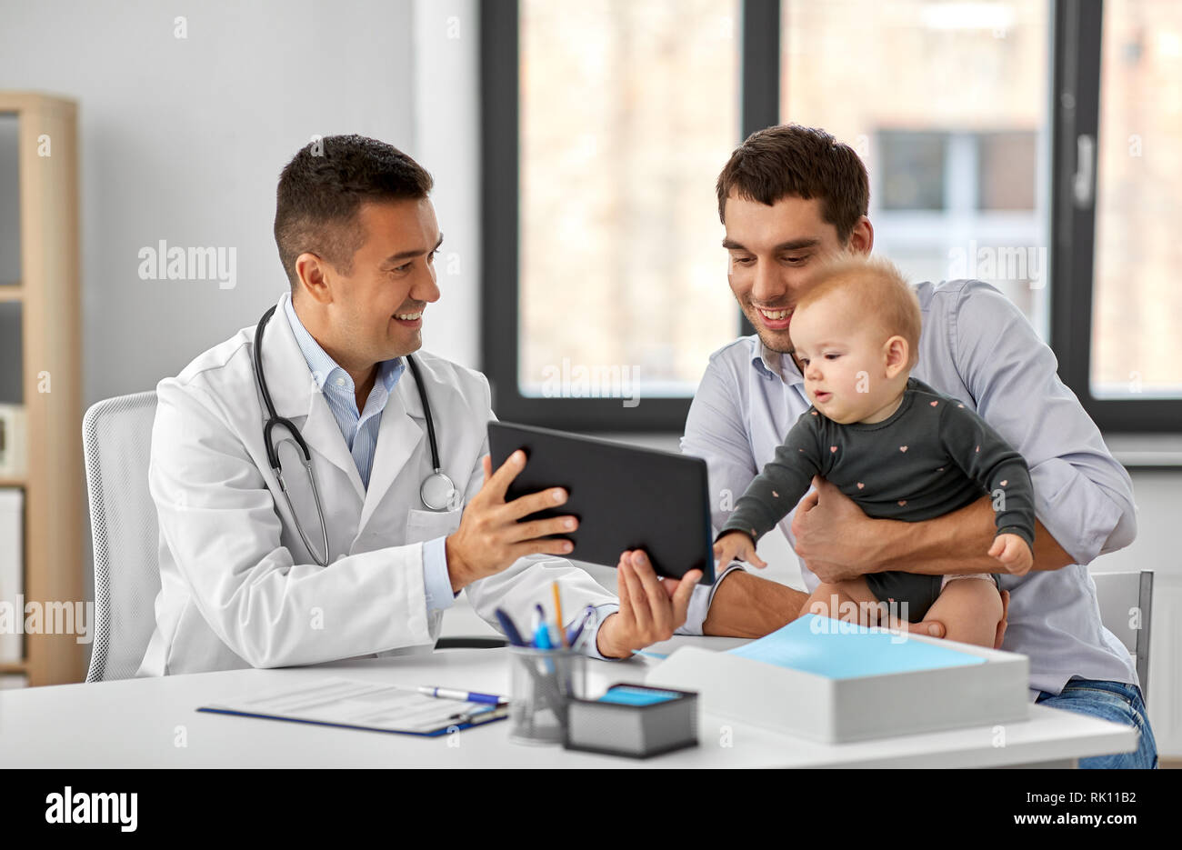 Padre con il bambino e il medico con una compressa alla clinica Foto Stock