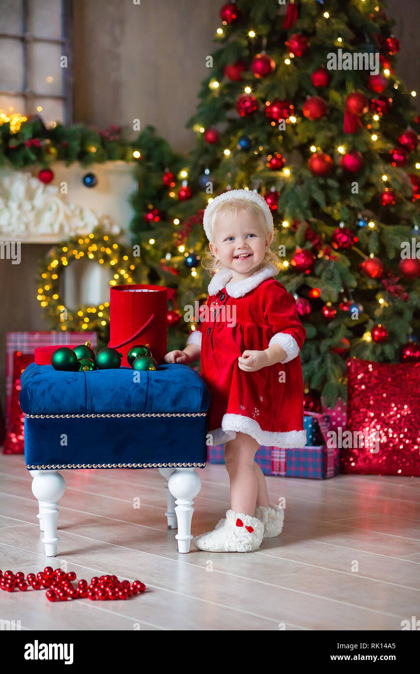 Buon Natale e Buone Feste grazioso fanciullo ragazza è decorare l'albero di Natale in ambienti interni Foto Stock