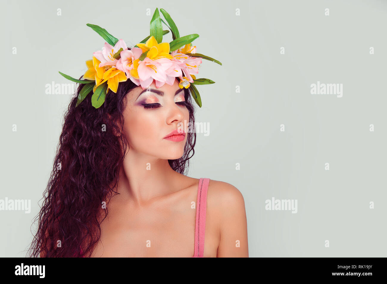 Closeup ritratto di donna con gli occhi chiusi che mostra il trucco colorato nella corona floreale sulla testa. Colombiano ispanica latina razza mista modello, brunette ricci Foto Stock