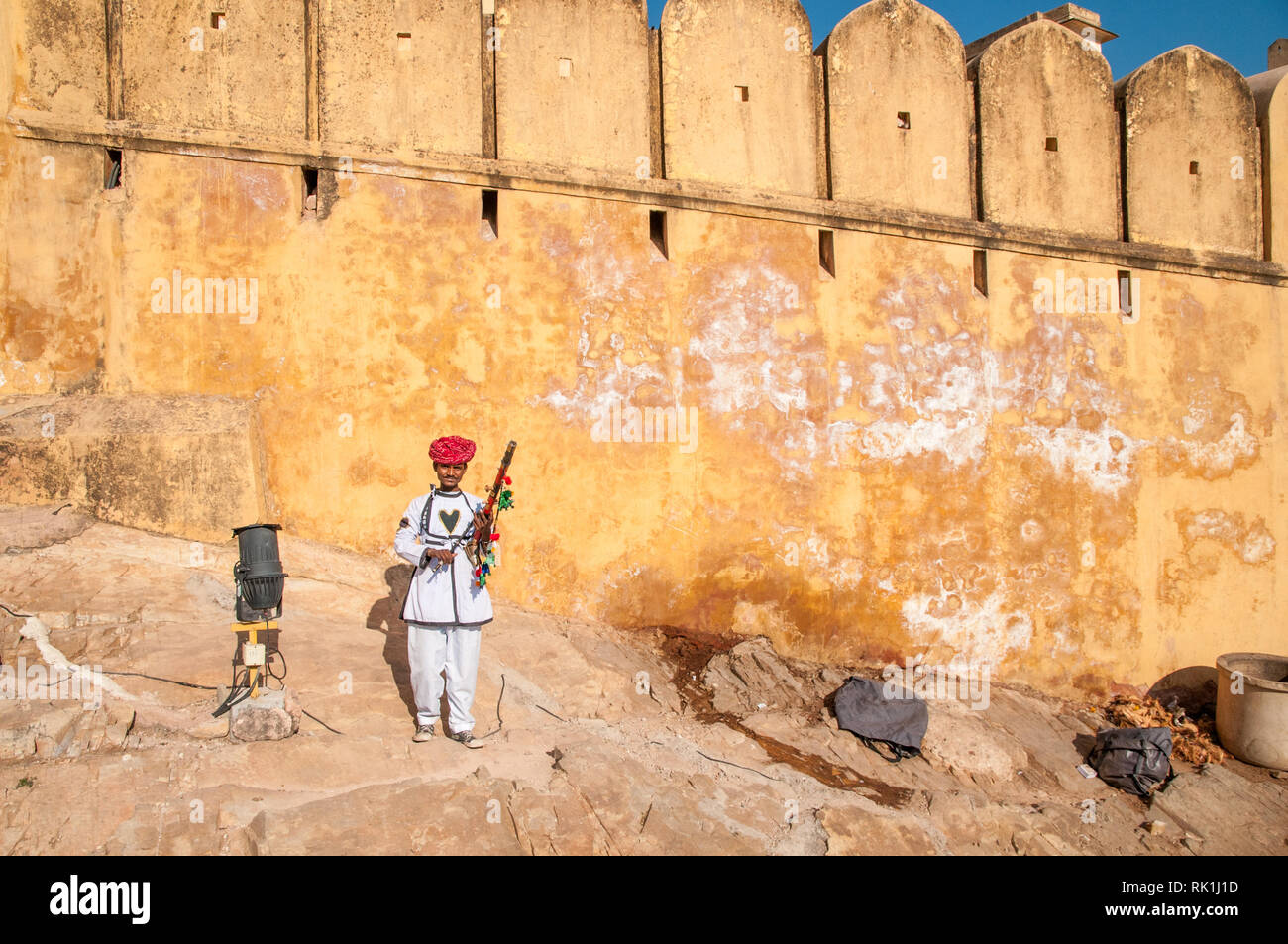 Uomo di Rajasthani con strumento tradizionale fuori Forte Amer, completata nel 1592 è stata la residenza dei Rajput Maharajas in Jaipaur, India. Foto Stock