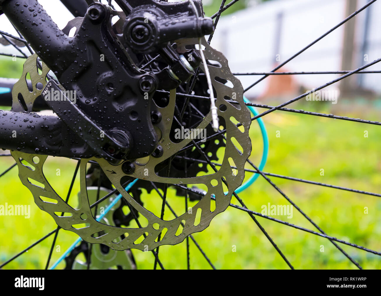 Bagnate dopo la pioggia una bicicletta il disco freno sull'erba verde dello sfondo. Foto Stock