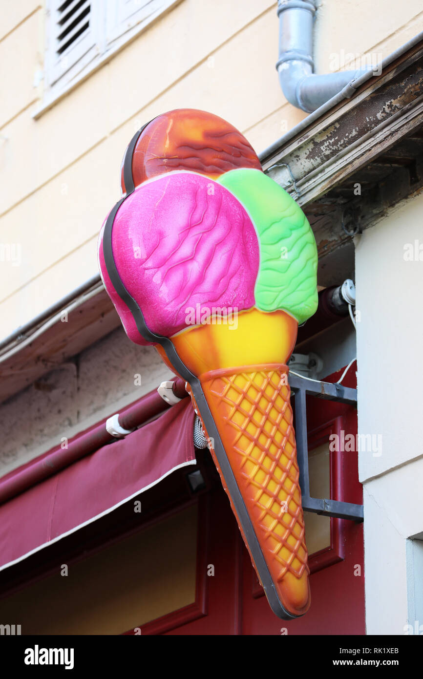 Colorate in plastica finto cono gelato sulla parete di un gelato Shop In Francia, in Europa. Vista ravvicinata Foto Stock