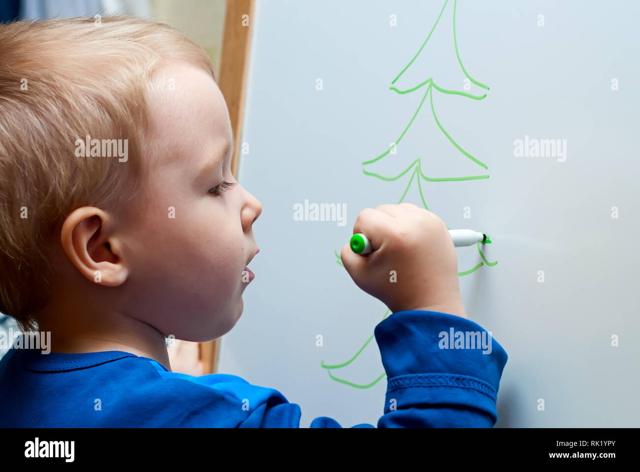 Il bambino impara a disegnare su una lavagna bianca colore pennarelli Foto Stock