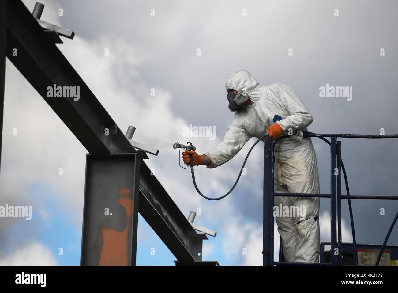 Tradesman vernici spray travi in acciaio su un sito in costruzione Foto Stock