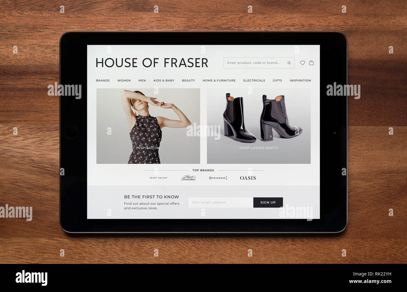 Il sito web di House of Fraser è visto su un tablet iPad, il quale è appoggiato su un tavolo di legno (solo uso editoriale). Foto Stock