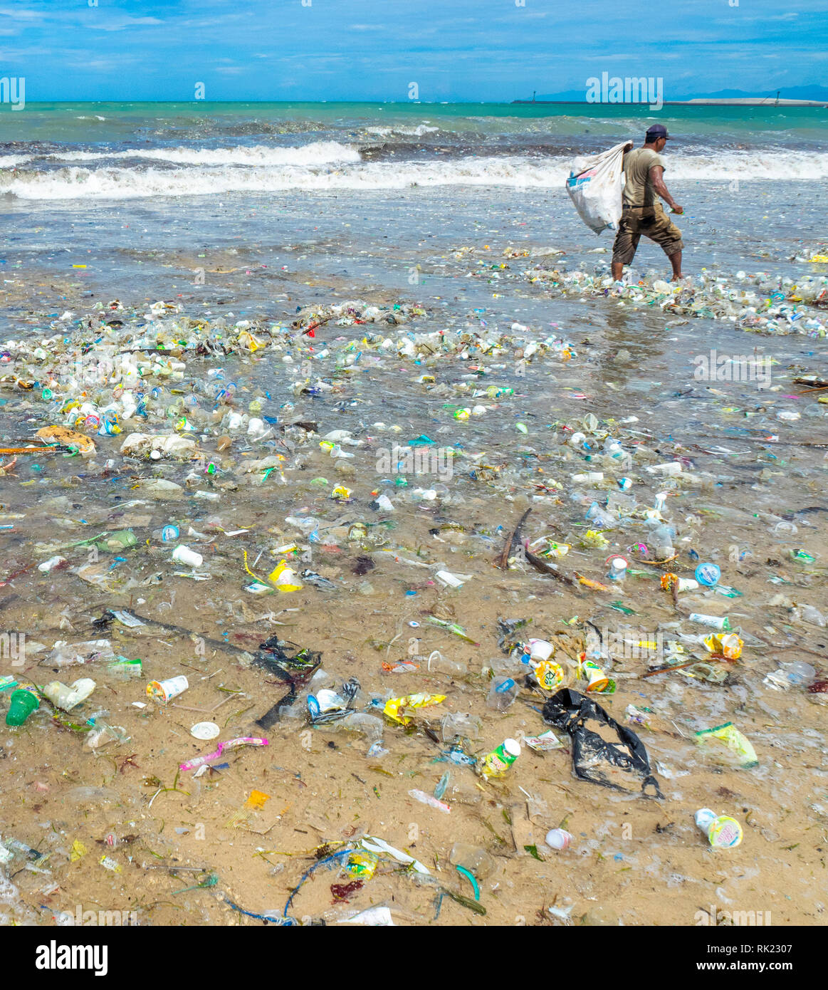 Inquinamento, lone uomo di prelevare le bottiglie di plastica, bicchieri, cannucce e altre lettiere lavato fino sulla spiaggia di Jimbaran, Bali Indonesia.. Foto Stock