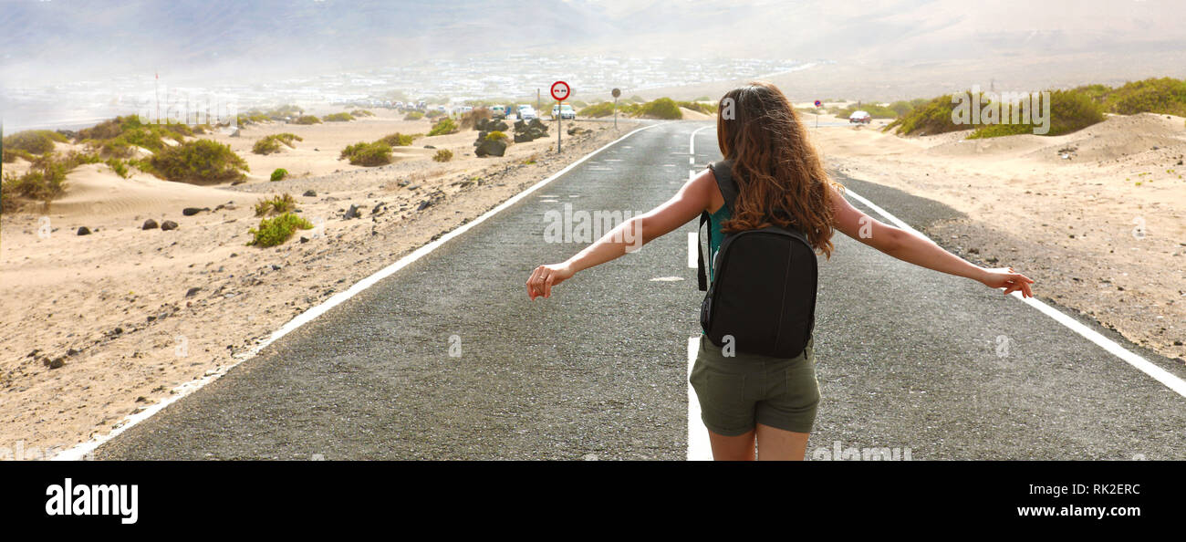 Credo di poter volare! Felice escursionista giovane donna con le braccia aperte sollevata sul deserto strada asfaltata. Panorama di banner. Foto Stock