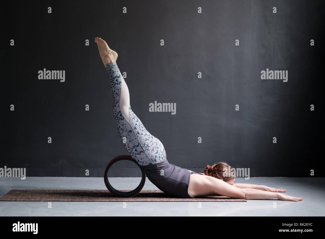 La donna a praticare yoga facendo Shalabhasana utilizzando ruote, Locust pone a piena lunghezza Foto Stock