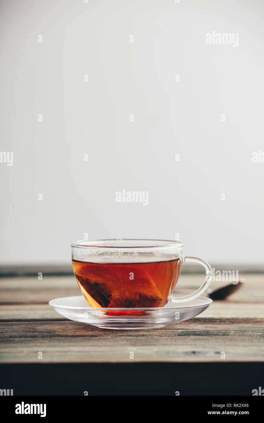 Un sacchetto da tè in una tazza. Una tazza di tè sul tavolo di legno contro il muro bianco Foto Stock