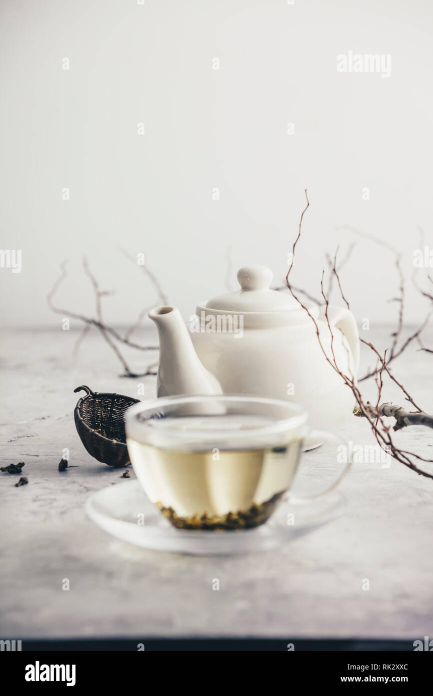 Composizione di tè con tazza di tè verde e bianco teiera contro il muro bianco Foto Stock