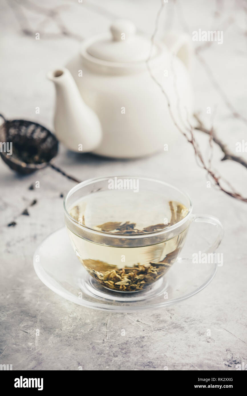 Composizione di tè con tazza di tè verde e bianco teiera contro il muro bianco Foto Stock