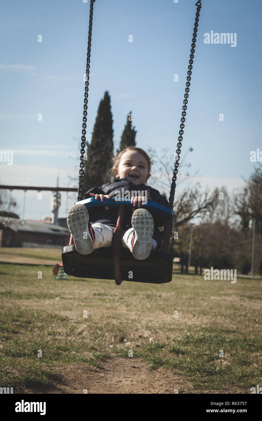 Bella ragazza toddler divertirsi su altalena nel parco. Foto Stock