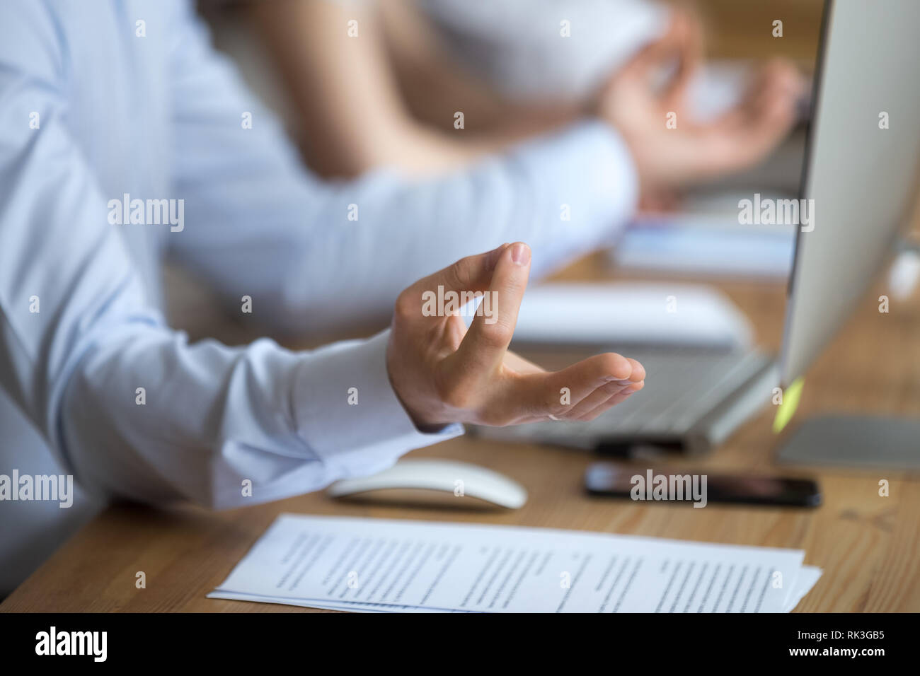 Calma uomo seduto alla scrivania in ufficio facendo esercizi yoga, primo piano Foto Stock