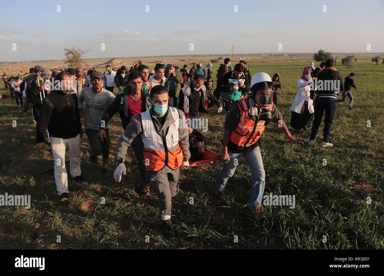 Lavoratori medici visto che trasportano un ferito durante gli scontri tra palestinesi e israeliane dopo una larga scala di marzo sulla recinzione di separazione tra Gaza e Israele a est di Khan Younis. Foto Stock