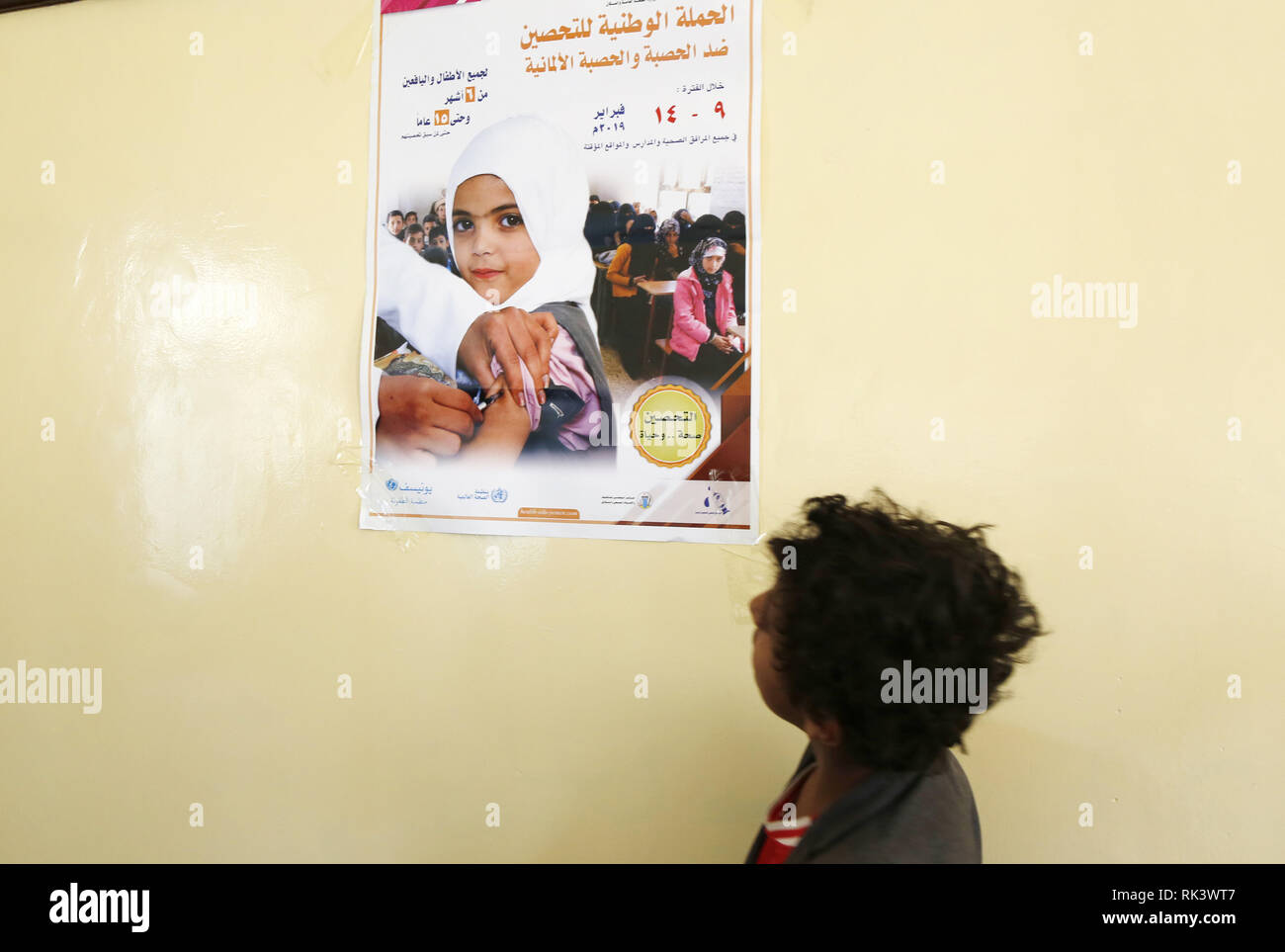 Sanaa, Yemen. Il 9 febbraio, 2019. Un bambino guarda un poster di sensibilizzazione prima di ricevere un anti-morbillo e il vaccino contro la rosolia in una scuola a Sanaa, Yemen, Febbraio 9, 2019. Un cittadino il morbillo e la rosolia campagna di immunizzazione sono iniziate il sabato in Yemen e avrà la durata di sei giorni. Il target della campagna yemenita ai bambini dai sei mesi ai 15 anni, secondo i media locali. Credito: Mohammed Mohammed/Xinhua/Alamy Live News Foto Stock