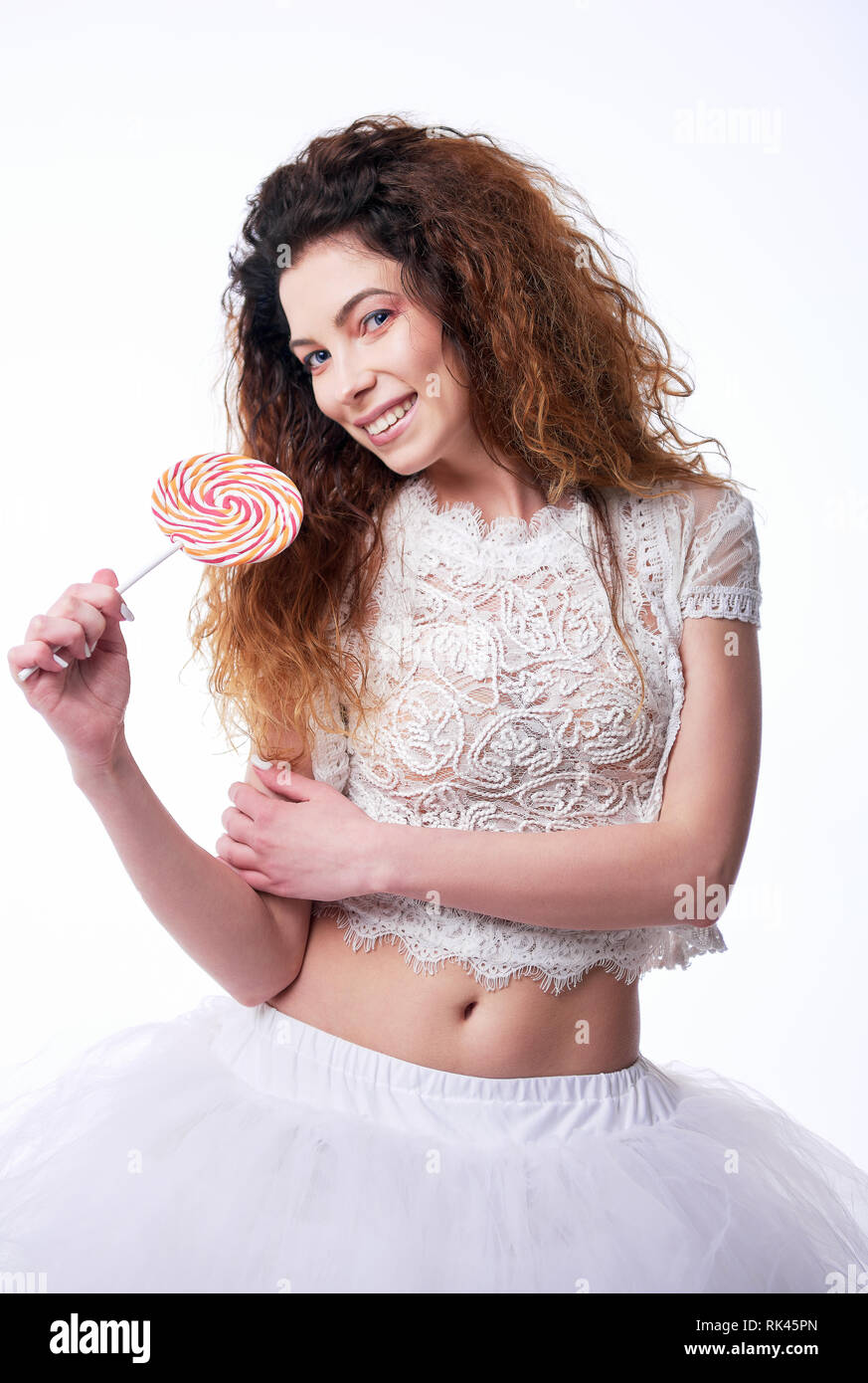 Ritratto di carino sorridente ragazza giovane mangiare lecca-lecca. Ritratto in studio su sfondo bianco Foto Stock