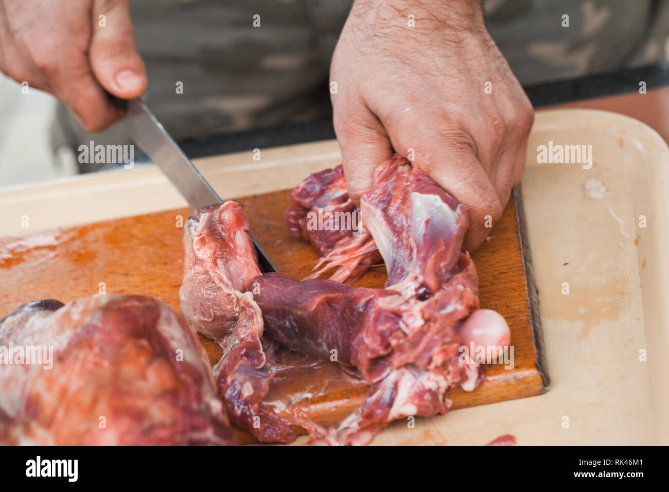 Materie di carne di agnello, taglio cuocere le mani con coltello, close-up foto Foto Stock