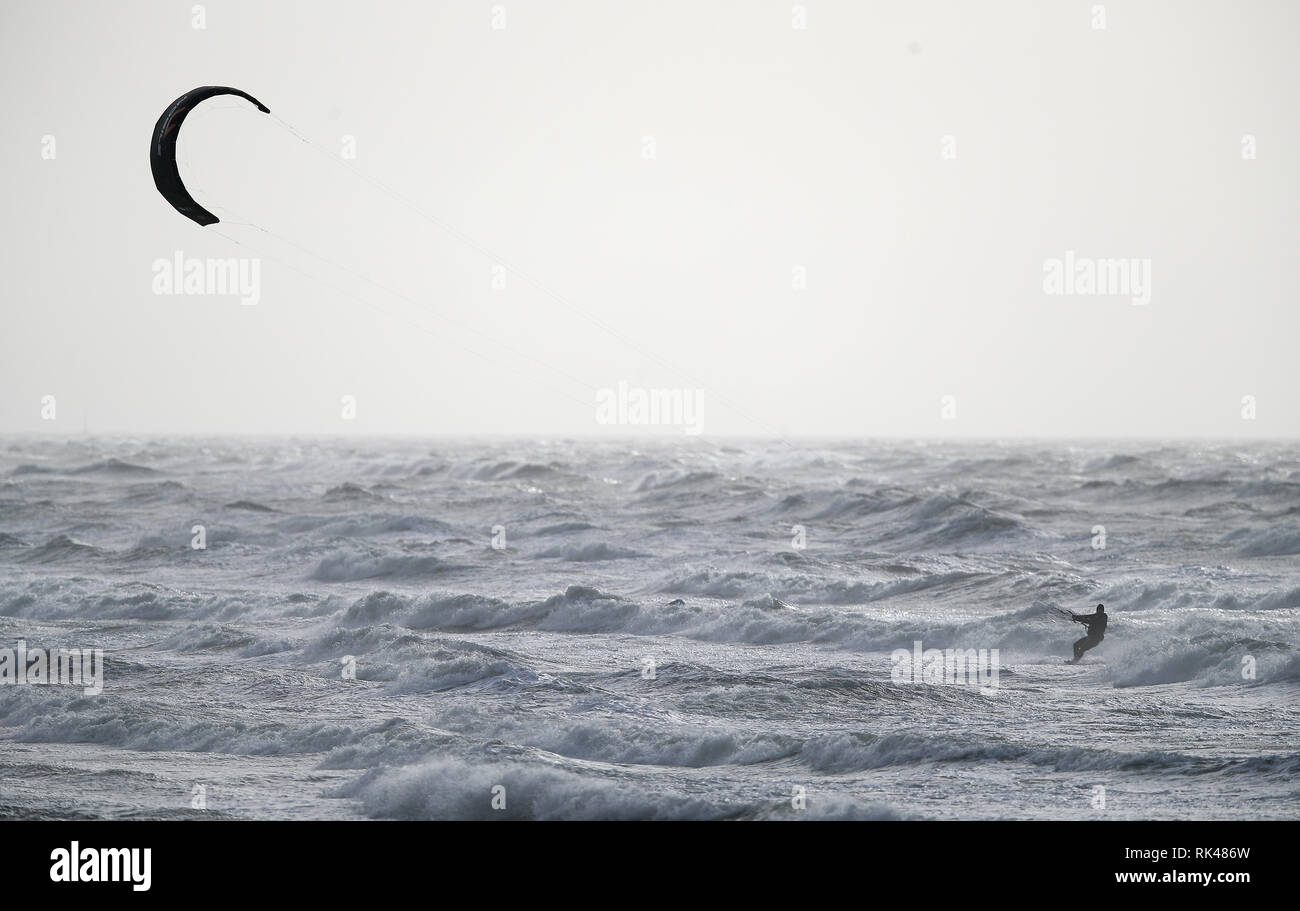 Un kite surfer che naviga in mare mosso al di fuori della baia di Bracklesham nel West Sussex, come tempesta Erik ha portato i forti venti a parti del paese. Foto Stock