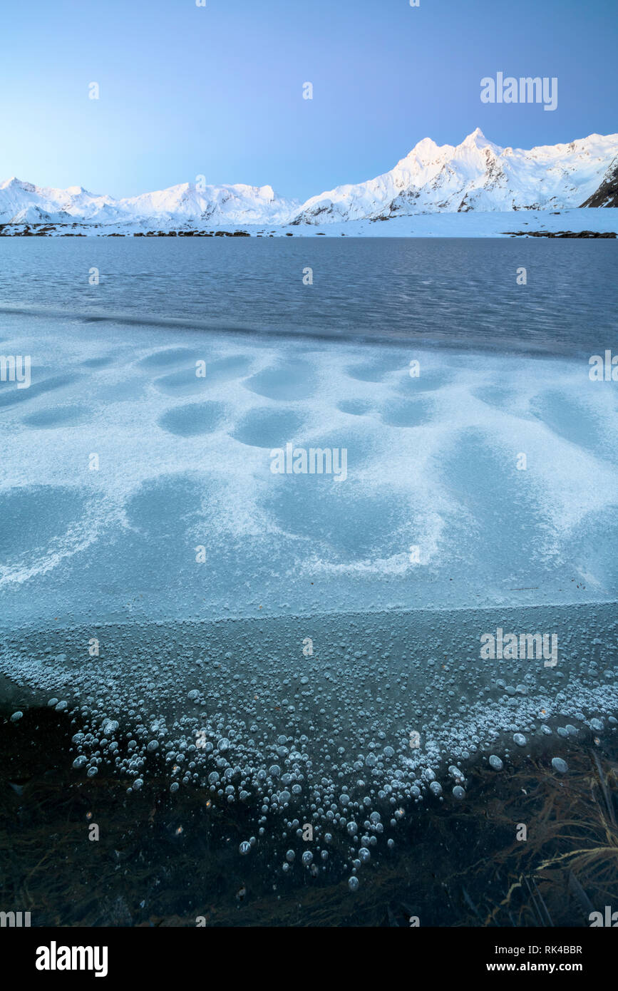 La superficie ghiacciata del lago Andossi con pizzi dei piani su sfondo, Valle Spluga, provincia di Sondrio e della Valtellina, Lombardia, Italia Foto Stock