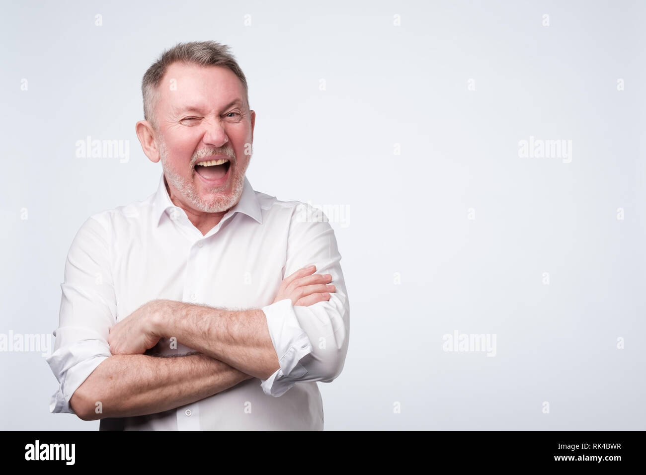 Sorridente anziano Uomo in camicia bianca in piedi in studio. Foto Stock