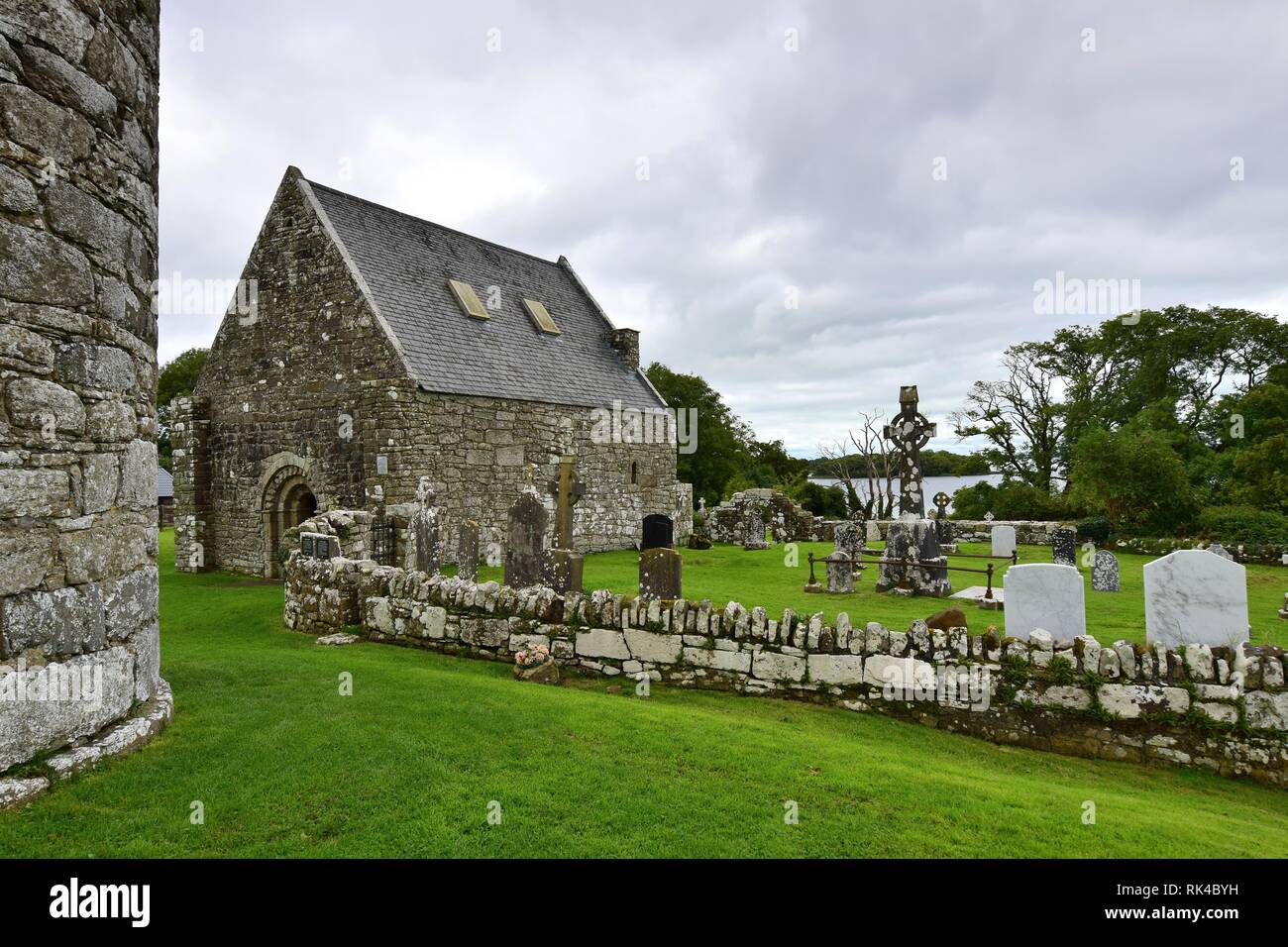 Le rovine di una chiesa più antica e un cimitero sulla Isola Santa del Lough Derg in Irlanda, nella contea di Clare. Sulla sinistra una parte di una torre rotonda. Foto Stock