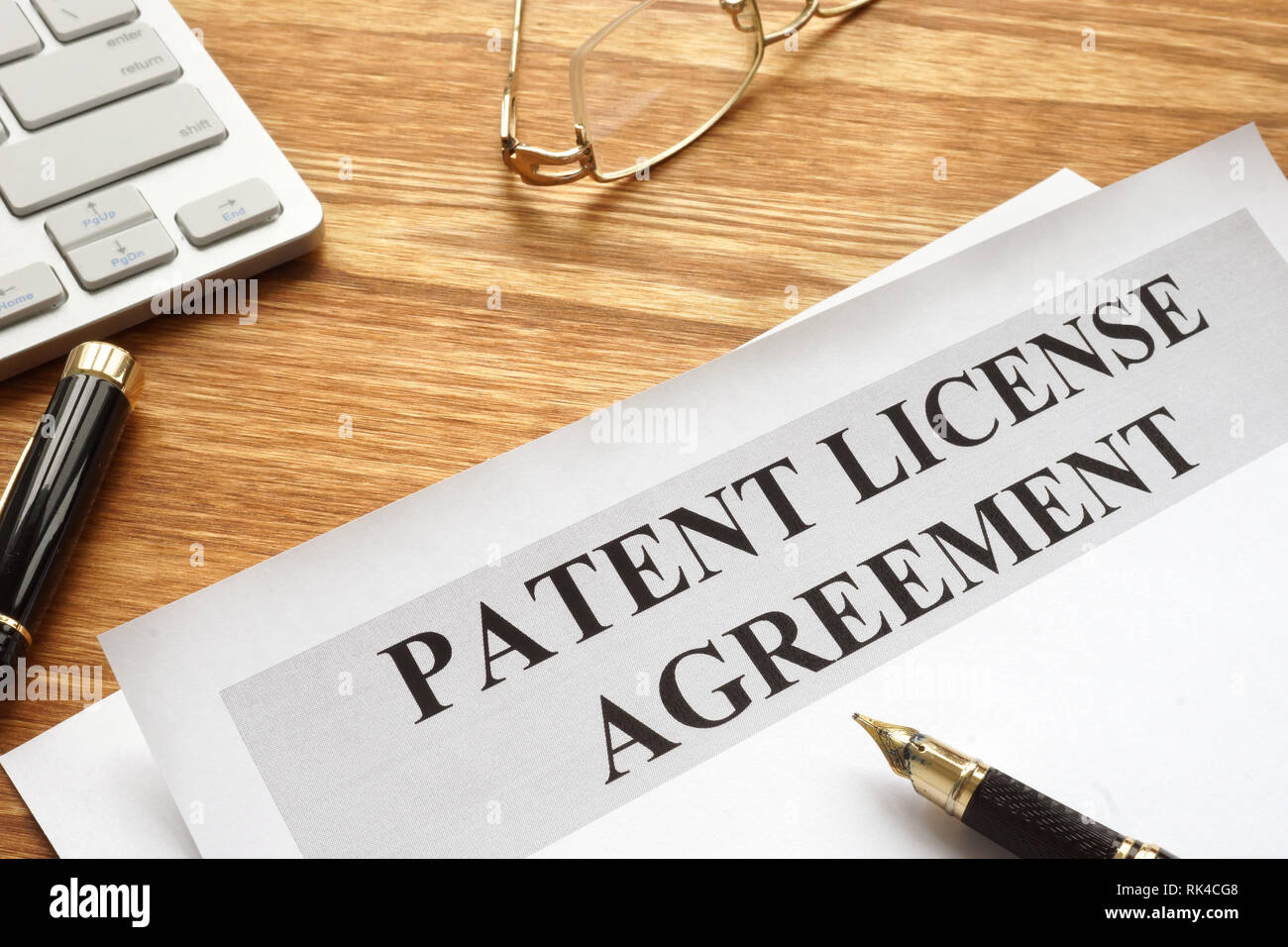 Accordo di licenza di brevetto con penna e bicchieri. Foto Stock