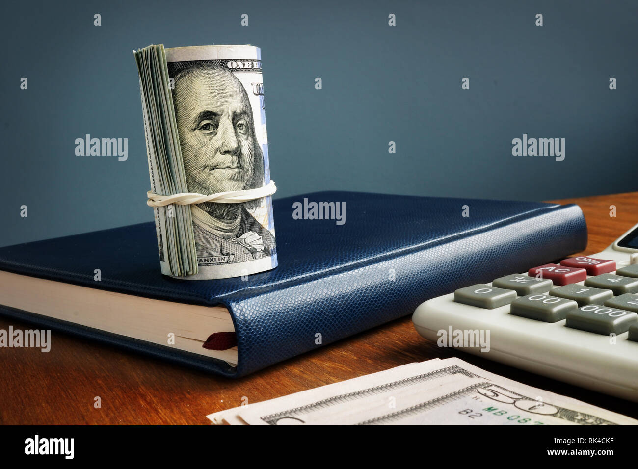 Arrotolato di dollari, calcolatrice e contabilità libro. Il concetto di risparmio. Foto Stock