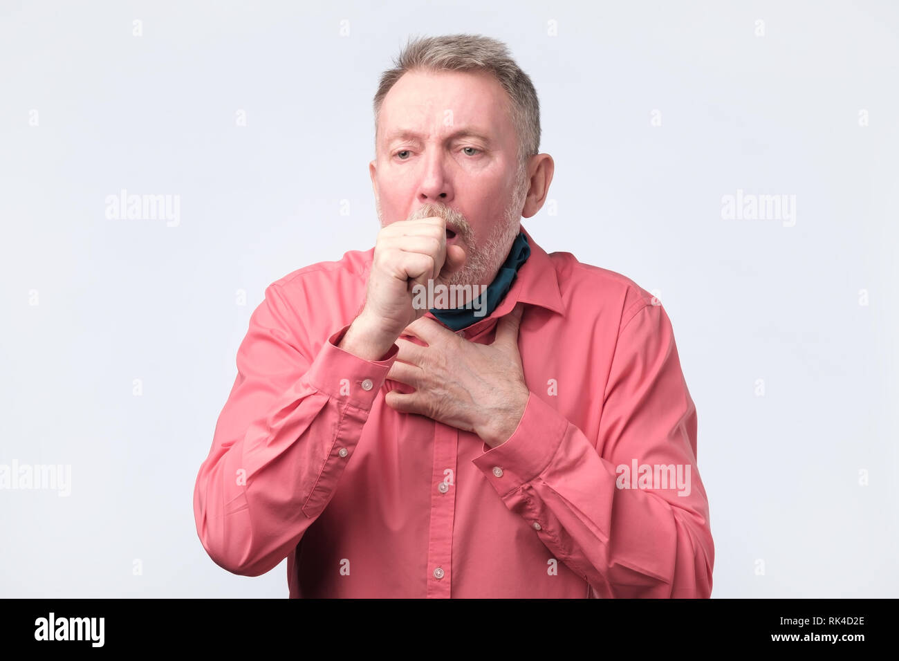 Gentiluomo europeo in maglietta rossa tosse perché di diseas polmonare Foto Stock