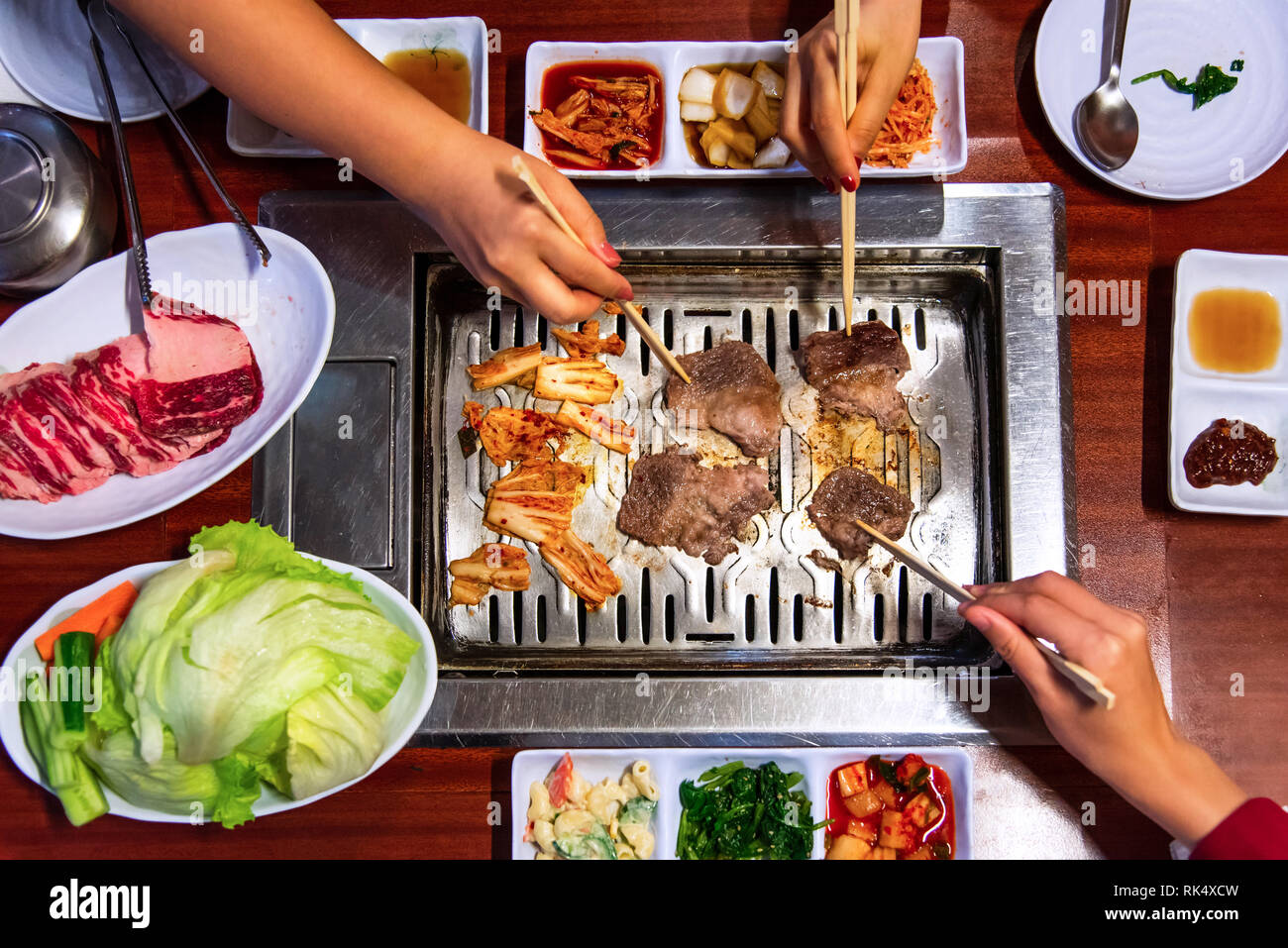 Le persone aventi barbeque Coreano e verdura vista superiore Foto Stock