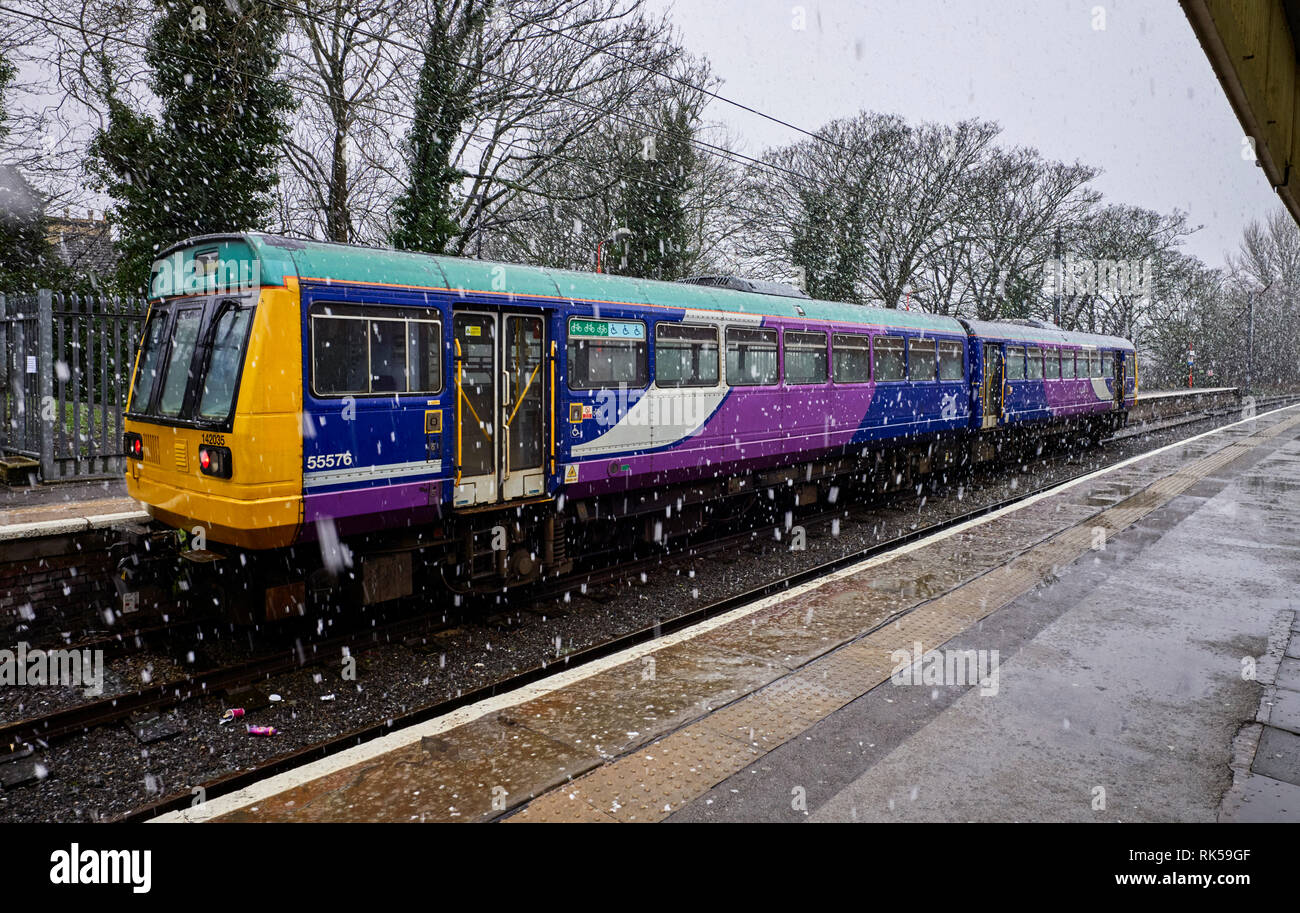 La neve che cade a Lancaster stazione dove un due auto bus tipo Pacer treno attende i passeggeri diretti al Porto di Heysham Foto Stock