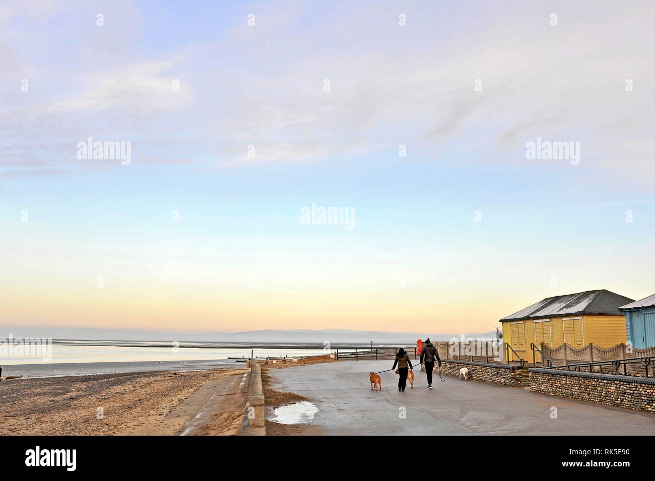 L uomo e la donna a piedi lungo i cani Fleetwood ione sul lungomare di un tardo pomeriggio in inverno Foto Stock
