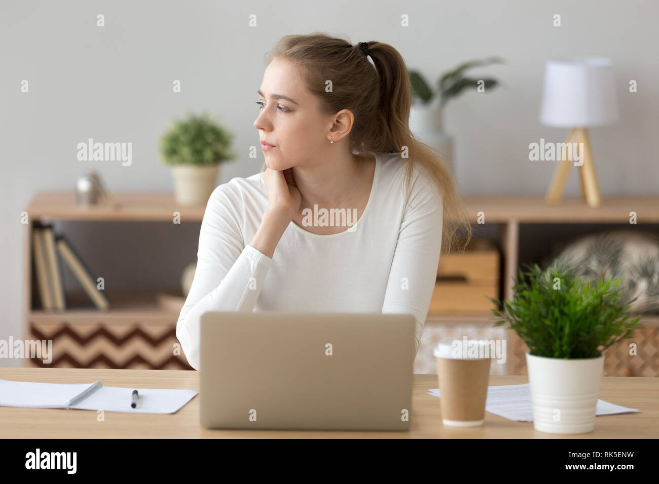 Grave donna che guarda lontano alla ricerca di nuove idee lavorando sul computer portatile Foto Stock