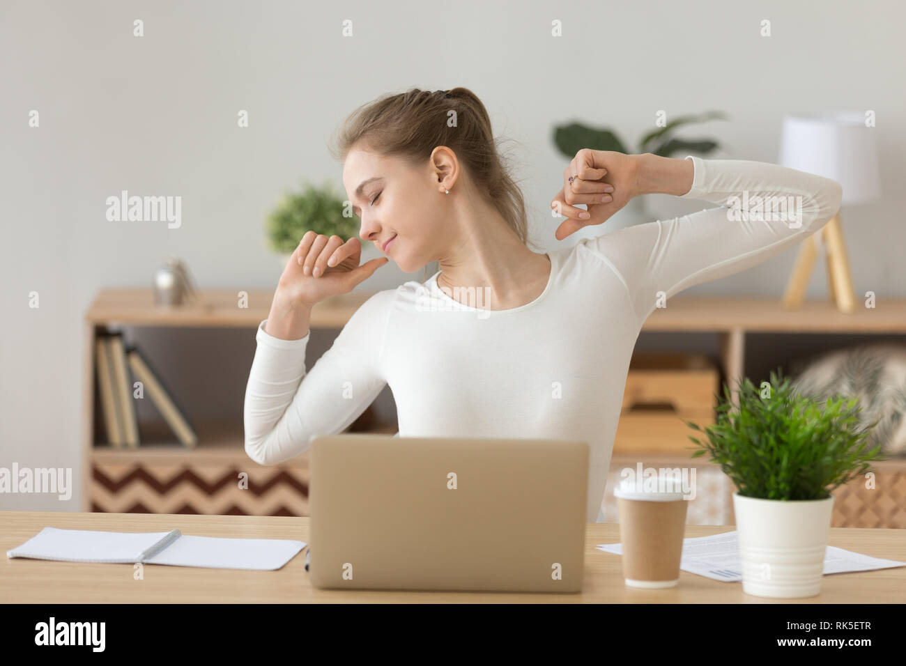 Rilassata donna stretching alla scrivania soddisfatto con il lavoro ben fatto Foto Stock