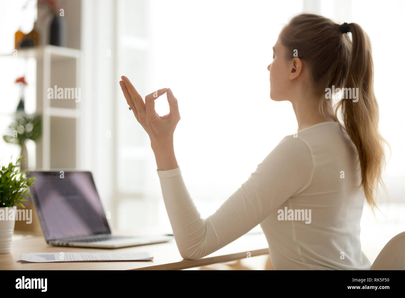 Serena calma sano donna seduta alla scrivania facendo esercizi yoga Foto Stock