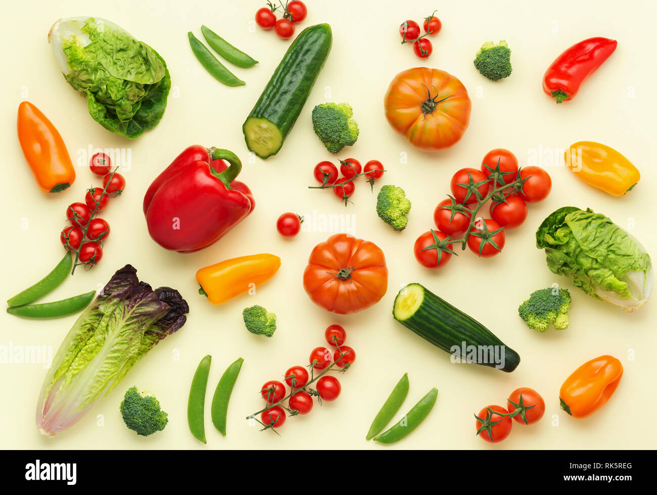 Freschi ingredienti grezzi per insalata Pomodori Cetrioli insalata di avocado pepe cipollina broccoli piselli su luce giallo tabella, vista dall'alto, il fuoco selettivo Foto Stock